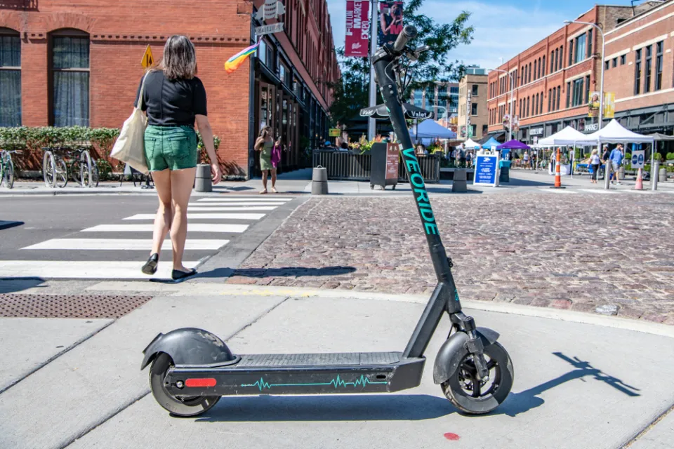 An electric scooter blocks the sidewalk near a street festival in Chicago's West Loop.